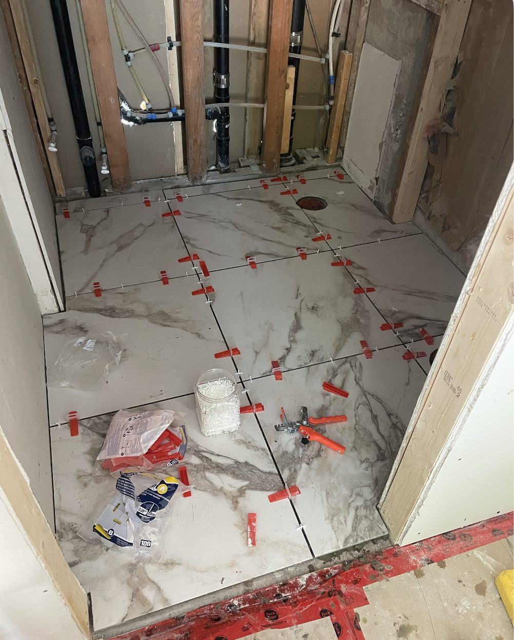 Marble-look porcelain floor tile installation with levelling system, bathroom renovation North Vancouver